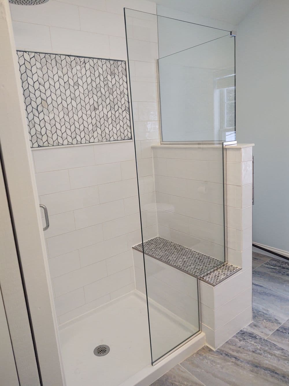 Modern shower design featuring glass enclosure, tiled wall, and built-in bench.