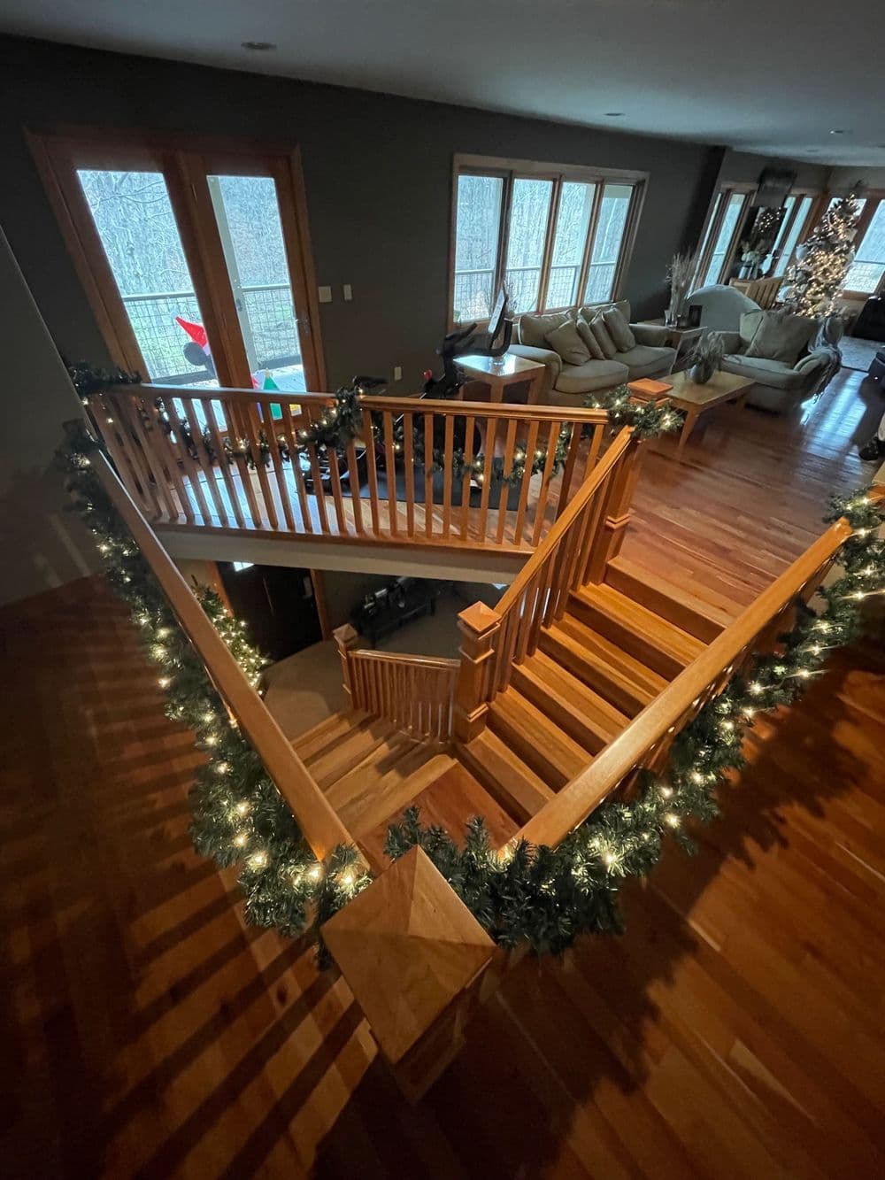 Spacious wooden staircase adorned with garland and lights, leading to a cozy living area.