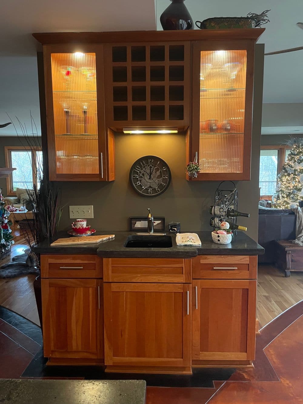 Modern kitchen wet bar with wood cabinetry, stone countertop, and decorative lighting.