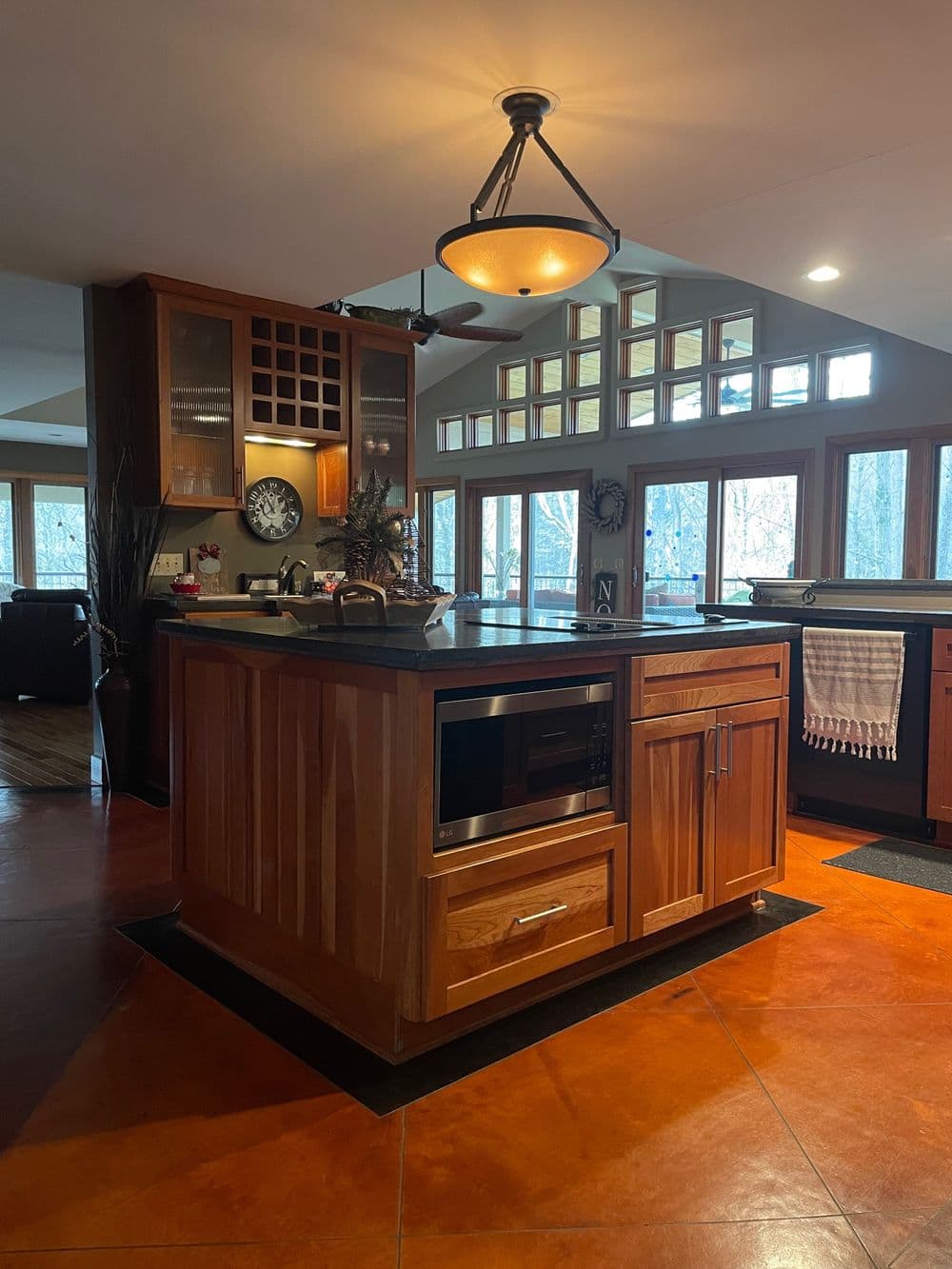 Modern kitchen featuring a wooden island with a dark countertop, large windows, and warm lighting.