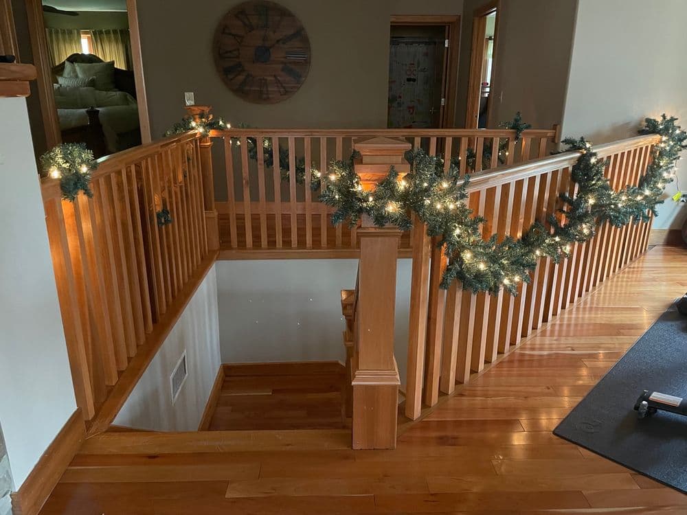 Wooden staircase with festive garland and lights, creating a warm, inviting atmosphere.