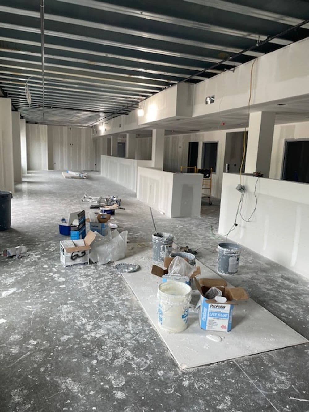Construction site with unfinished walls, tools, and supplies scattered across the floor.