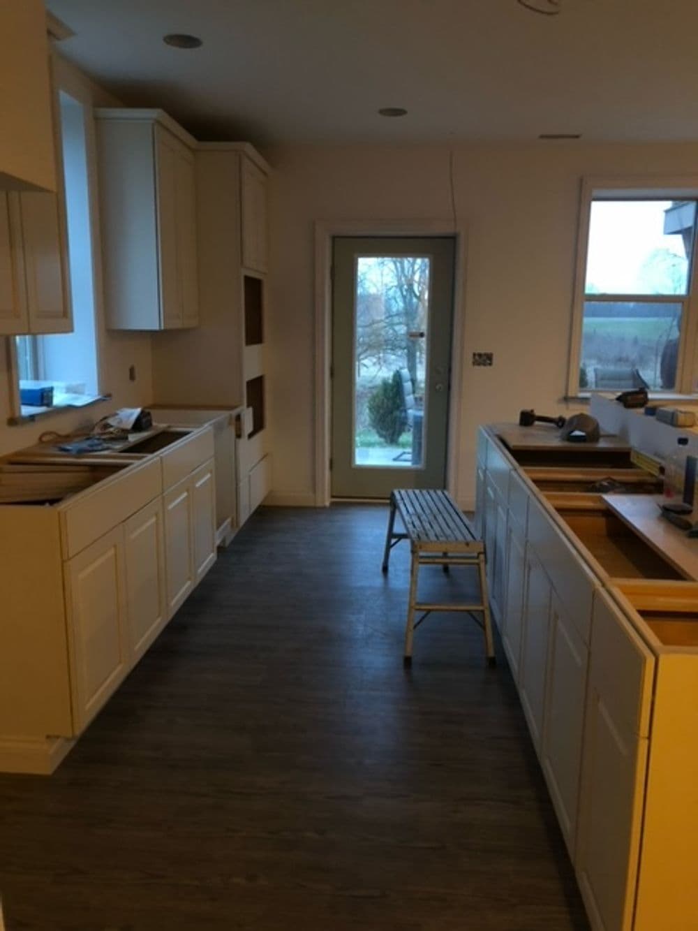 Modern kitchen renovation with white cabinetry, unfinished countertops, and patio door.