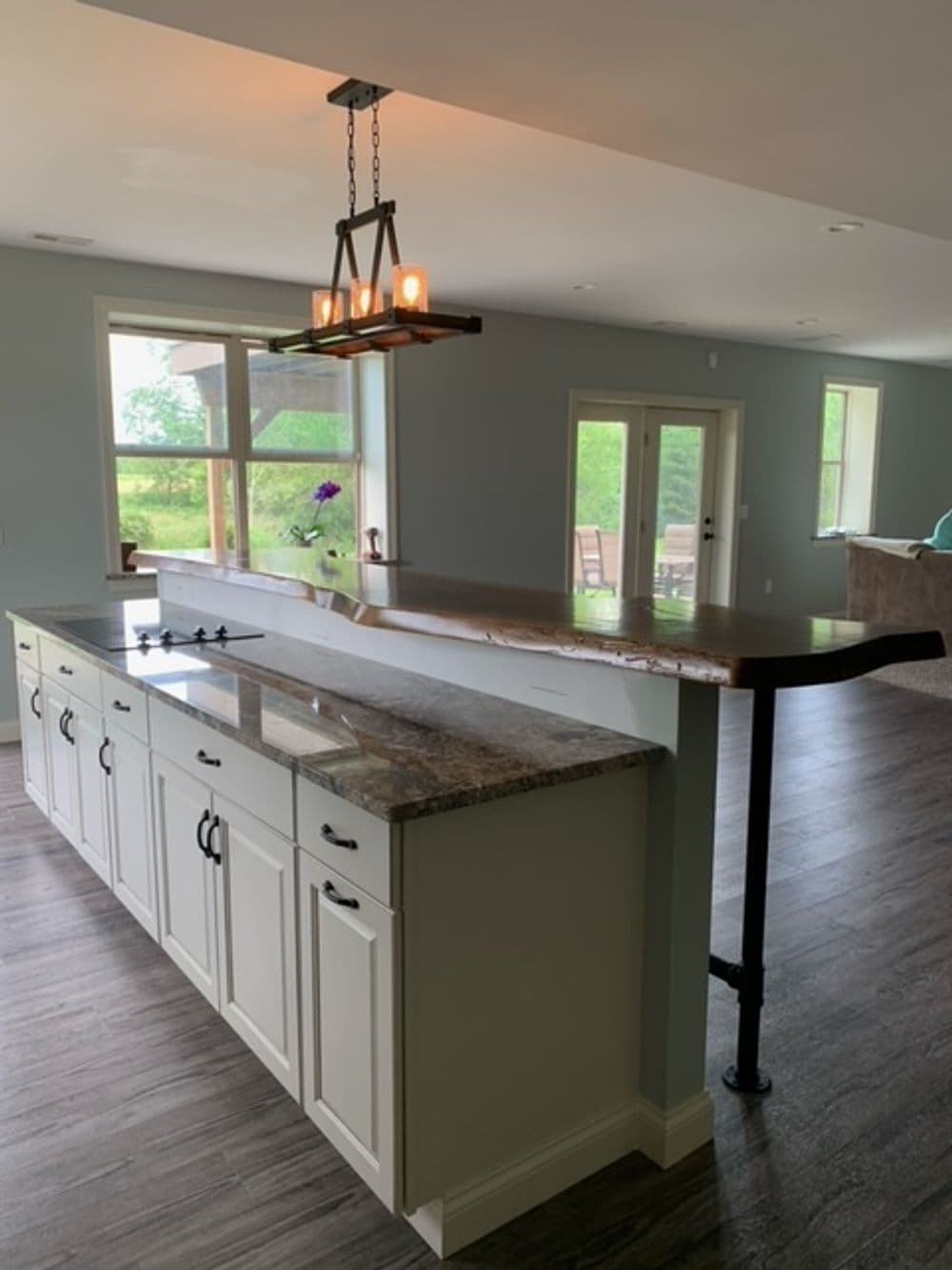 Modern kitchen with a granite counter, white cabinets, and a stylish pendant light fixture.