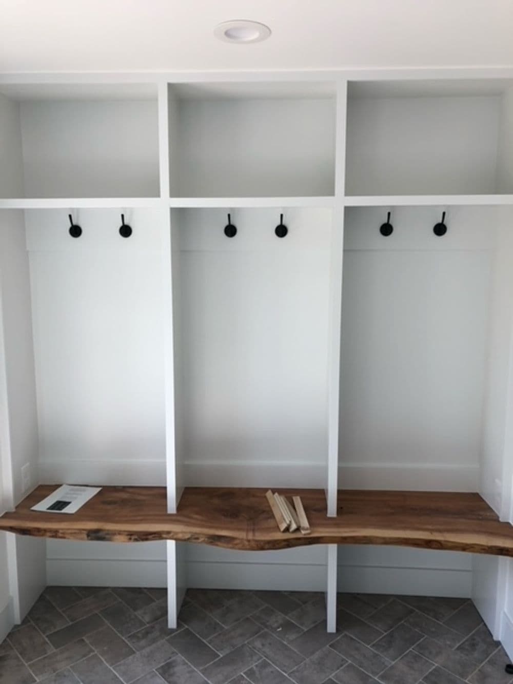 Modern mudroom interior with built-in shelves, wooden bench, and wall hooks.