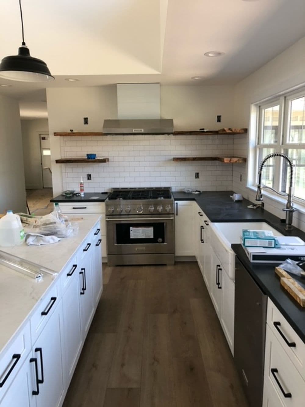Modern kitchen with stainless steel appliances, white cabinets, and wood shelving.